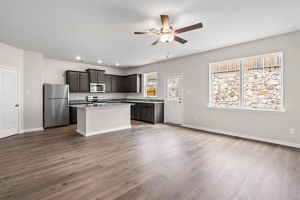 6307 Crosswood Lane, Dallas, TX 75241 Kitchen with stainless steel appliances, a center island, dark brown cabinets, light wood finished floors, and a ceiling fan