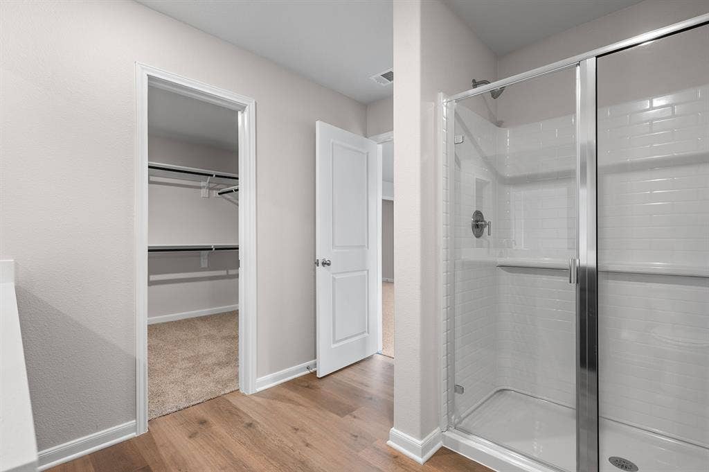6307 Crosswood Lane, Dallas, TX 75241 Bathroom featuring a stall shower, light wood-style floors, and a spacious closet
