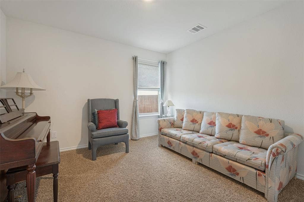 Neutral wall palette, carpeting, and a single window featuring horizontal blinds