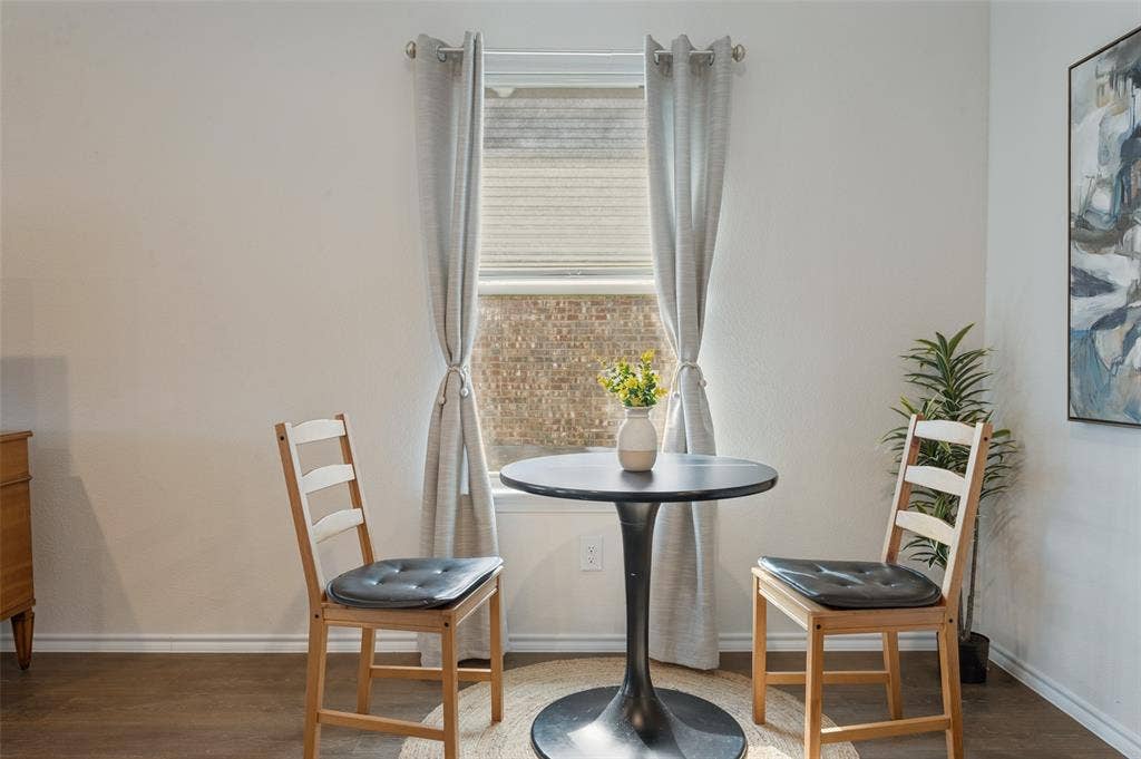 Single-hung window with neutral-toned window treatments and wood-finish flooring