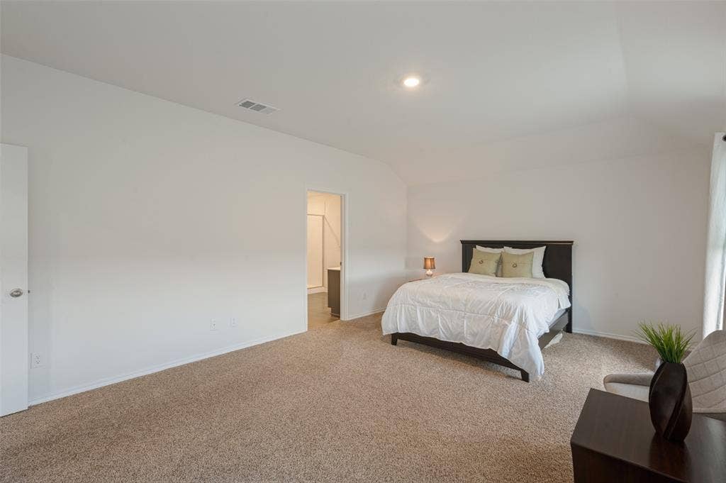 Neutral-toned carpeting, vaulted ceiling, and recessed lighting