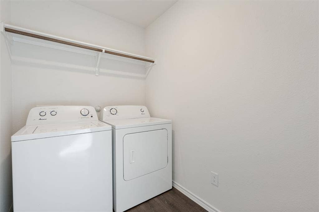 Laundry room featuring a built-in overhead shelf with hanging rod and wood-finish flooring