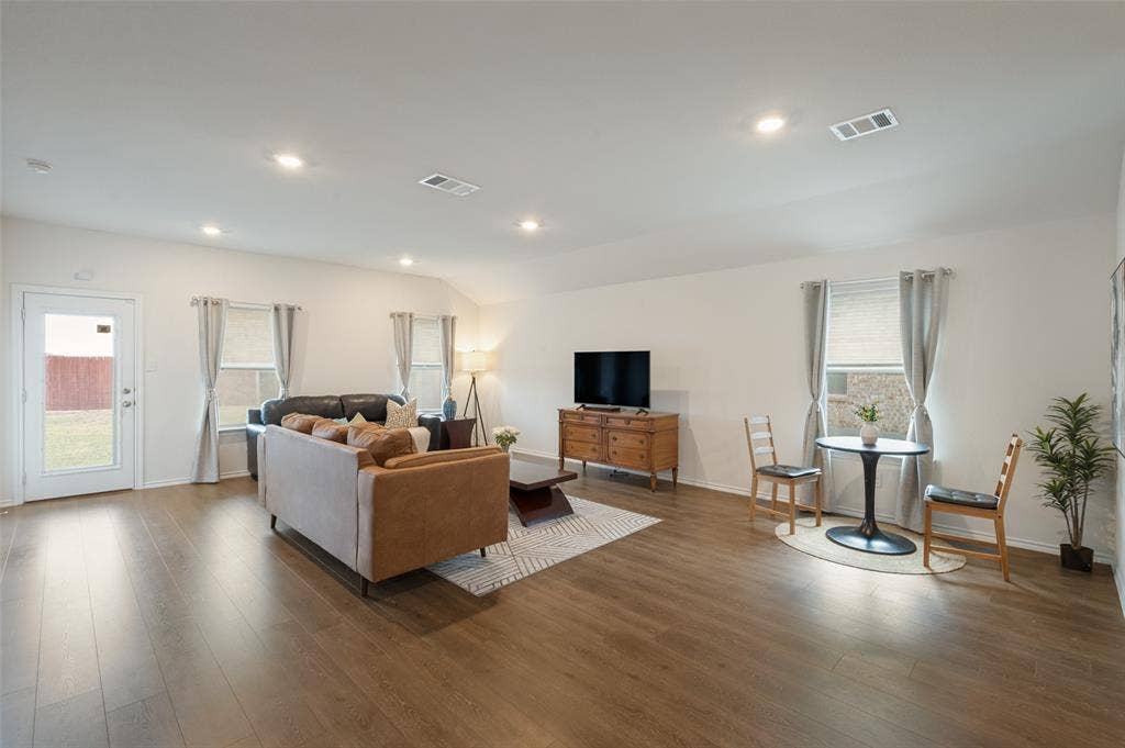 Open-concept room featuring wood-finish flooring, recessed lighting, and multiple windows with neutral window treatments