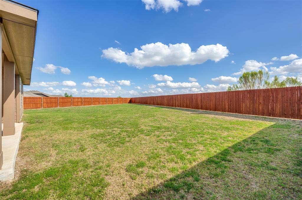 Spacious backyard featuring a level lawn, concrete patio, and a full-perimeter wood privacy fence