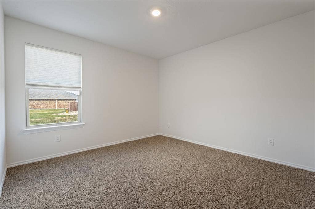 Neutral-toned wall-to-wall carpeting, crisp white walls, recessed ceiling lighting, and a window featuring a pleated shade