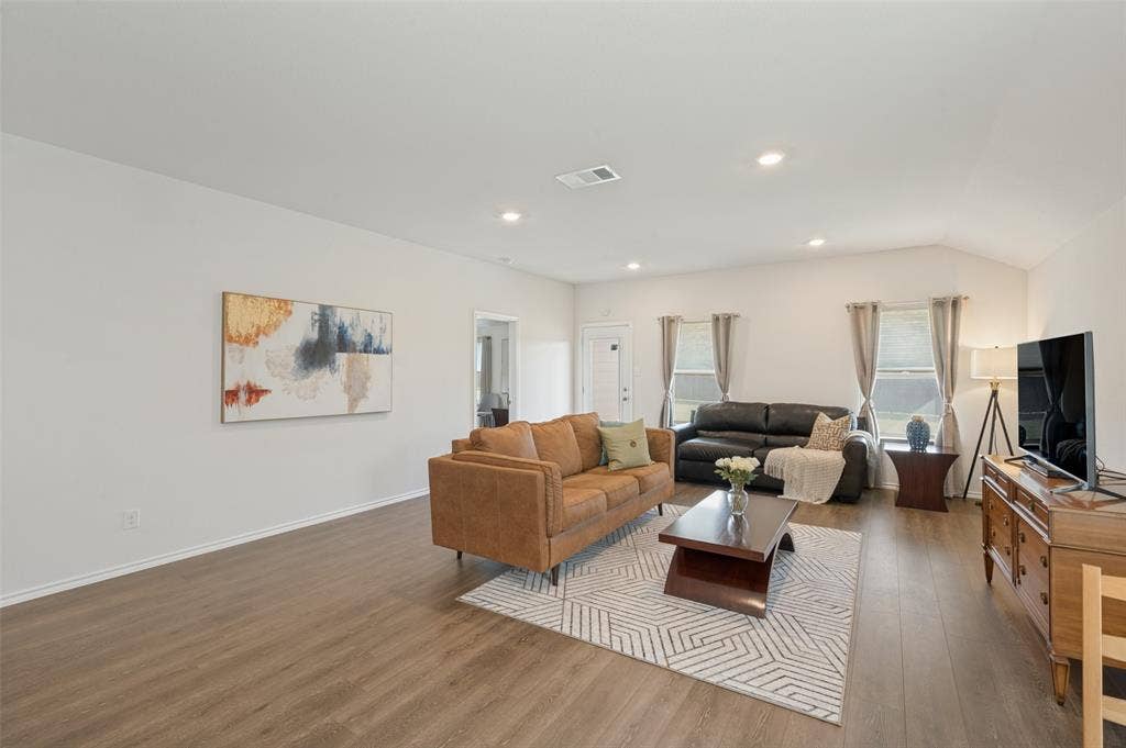 Neutral interior space featuring wood-finish flooring, high ceilings, and recessed lighting