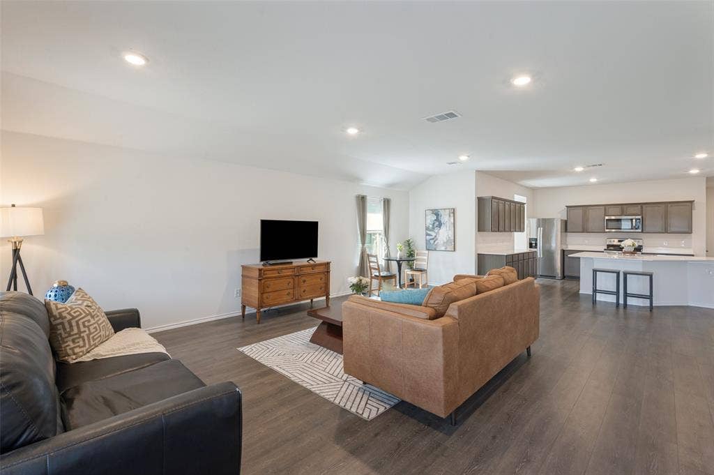 Open-concept interior featuring wood-finish flooring, recessed lighting, and a kitchen island with stone-finish countertops