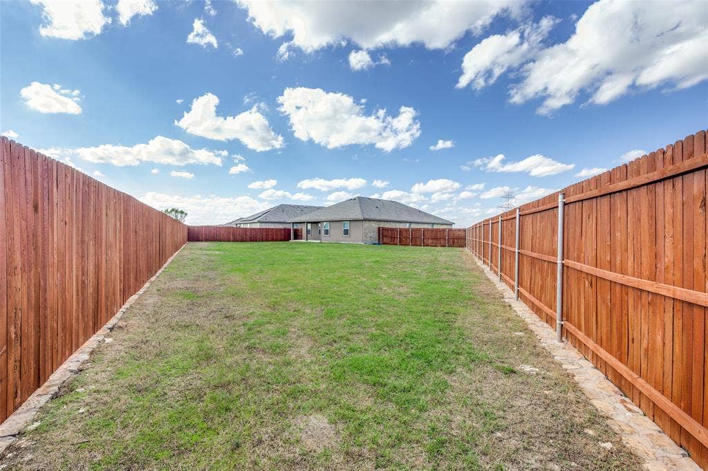 Expansive backyard featuring a full-perimeter wood privacy fence and a stone border