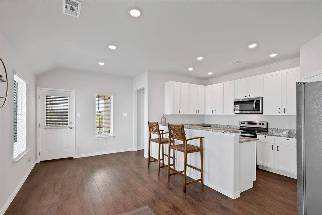 Kitchen featuring white shaker-style cabinetry, stone-surface countertops, recessed lighting, and wood-finish flooring