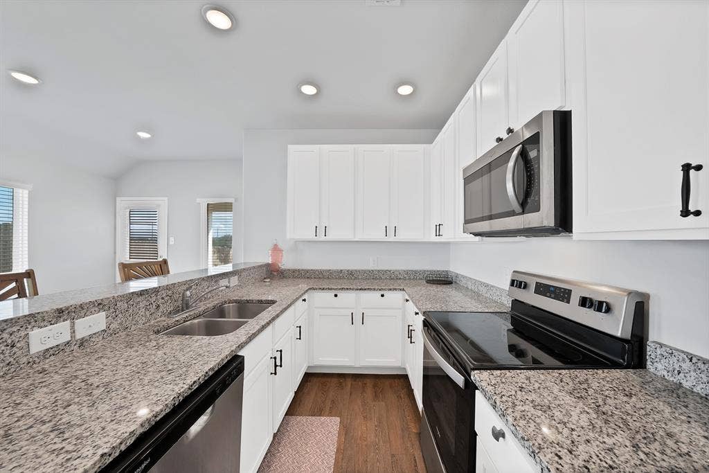 Kitchen featuring white cabinetry, stone-surface countertops, wood-finish flooring, stainless steel appliances, and recessed lighting