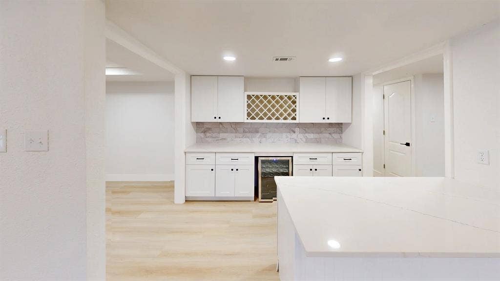 1506 W Spring Creek Parkway, Plano, TX 75023 White shaker-style cabinetry, integrated wine refrigerator, built-in wine rack, quartz countertop, and patterned stone-finish backsplash
