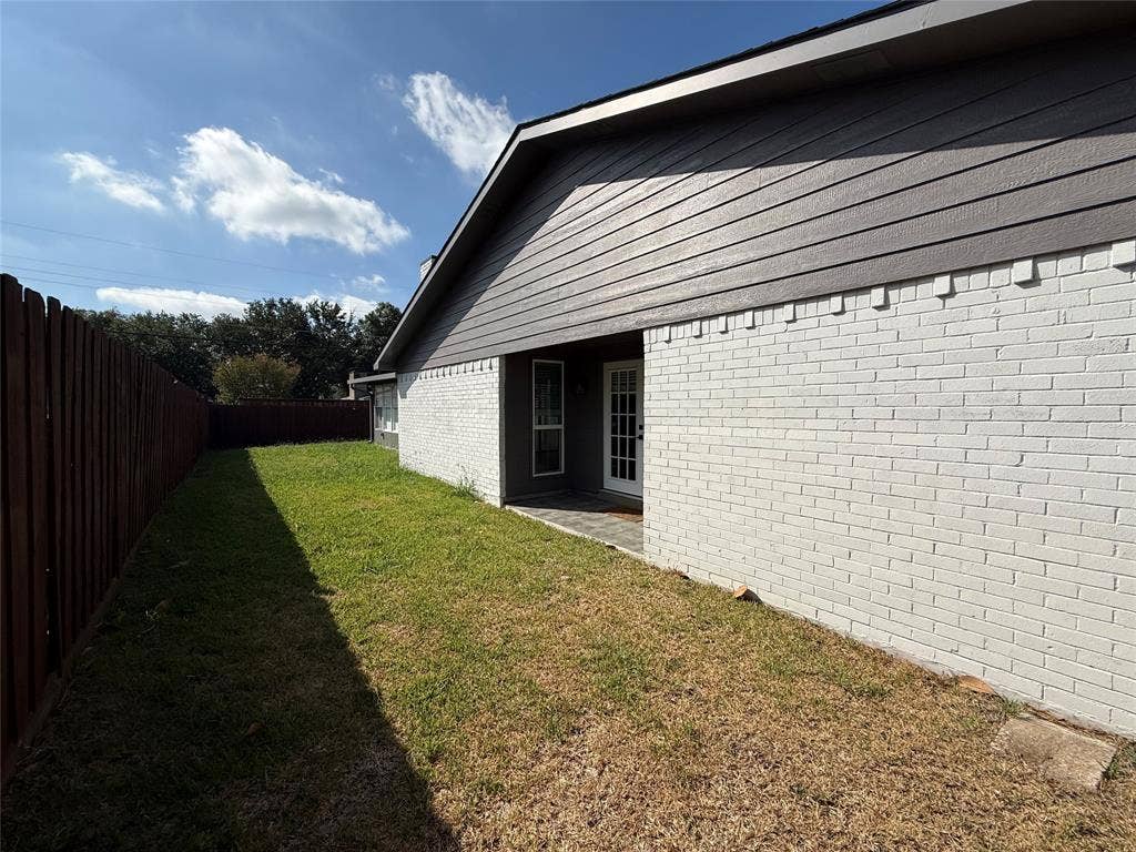 1506 W Spring Creek Parkway, Plano, TX 75023 Side yard featuring white painted brick exterior, horizontal siding, and wooden privacy fencing