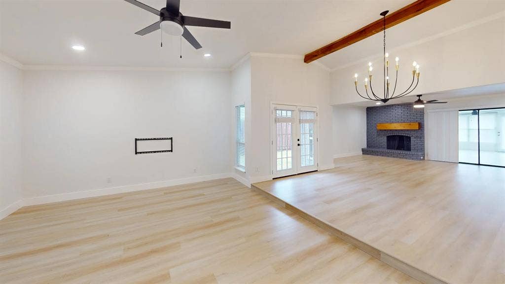 1506 W Spring Creek Parkway, Plano, TX 75023 Vaulted ceiling with exposed decorative wood beam, wood-finish flooring, metal multi-arm chandelier, and floor-to-ceiling brick fireplace with a wood mantel
