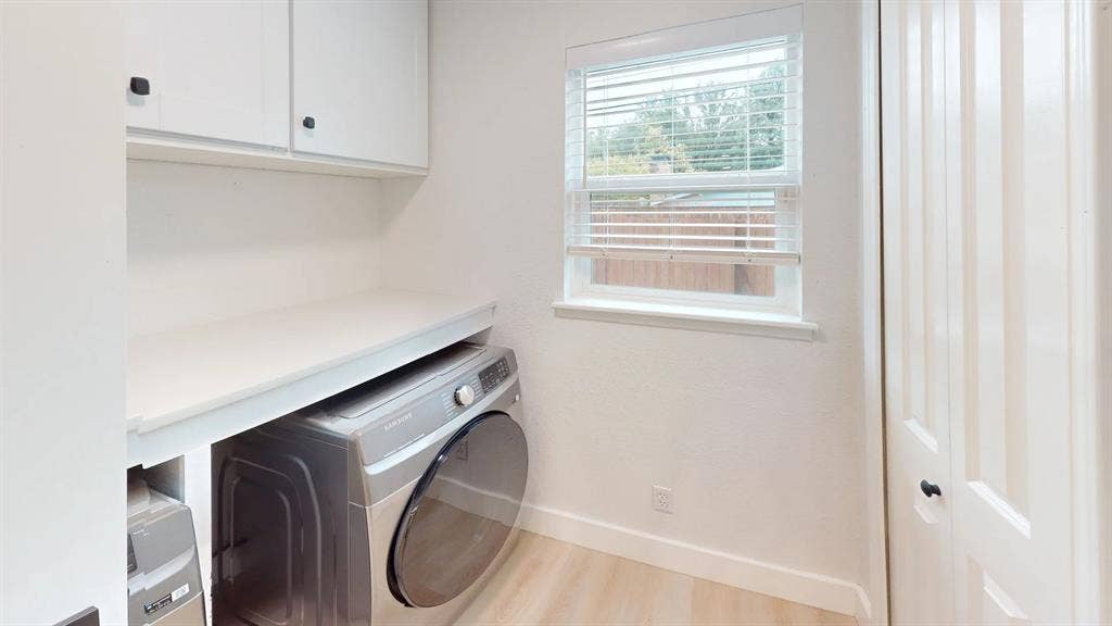1506 W Spring Creek Parkway, Plano, TX 75023 Utility room featuring white shaker-style upper cabinetry, a solid-surface folding counter, wood-finish flooring, and a louvered bi-fold closet door