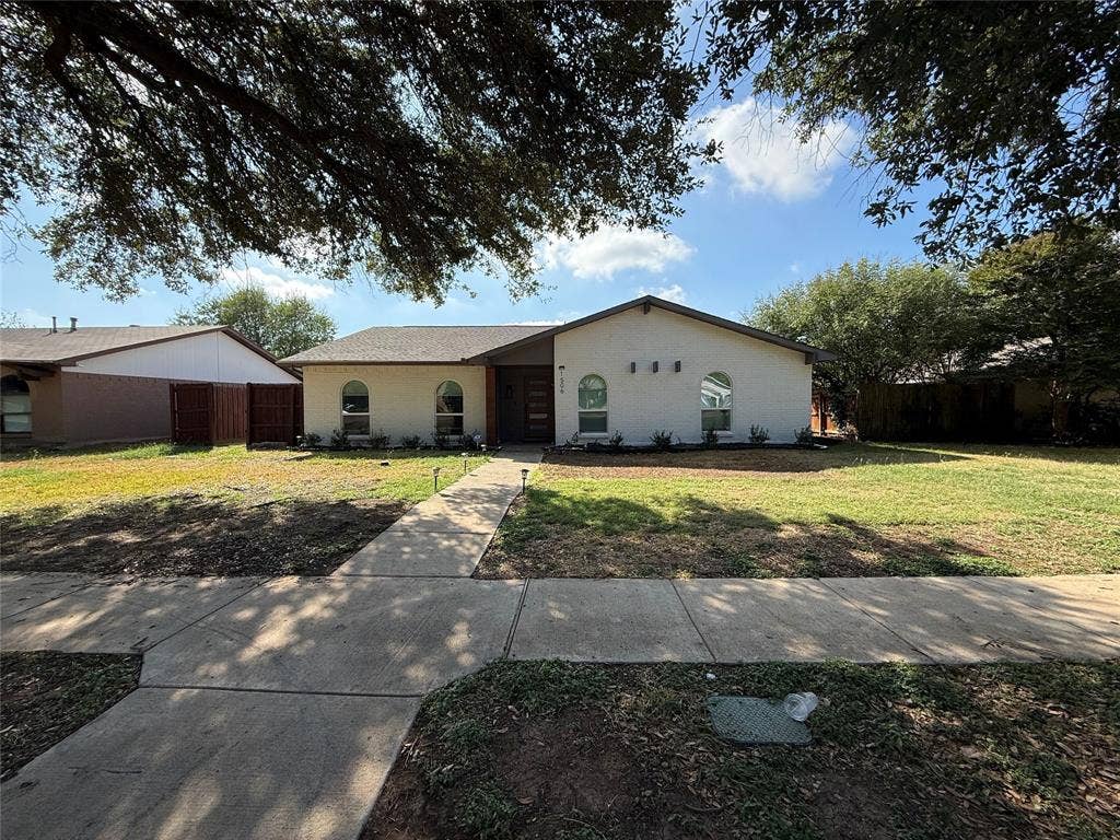 1506 W Spring Creek Parkway, Plano, TX 75023 Single-story residence featuring a light-toned exterior, arched windows, a covered entryway, and a concrete walkway