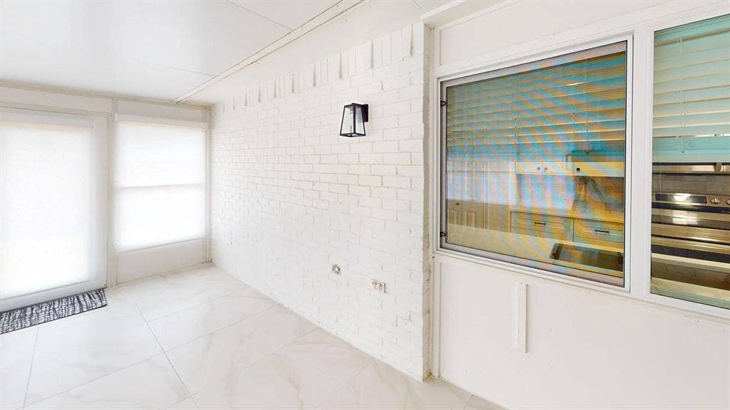 1506 W Spring Creek Parkway, Plano, TX 75023 Enclosed sunroom featuring white painted brick walls, large format tile flooring, and wall-mounted exterior-style lantern lighting