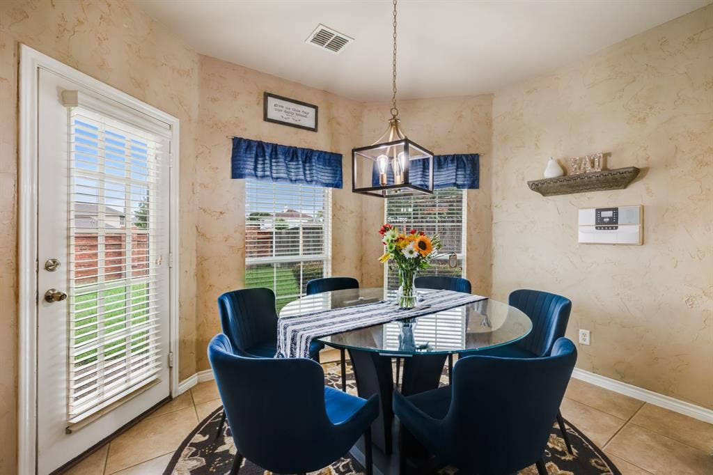 Tiled dining space featuring wallpapered walls and a chandelier