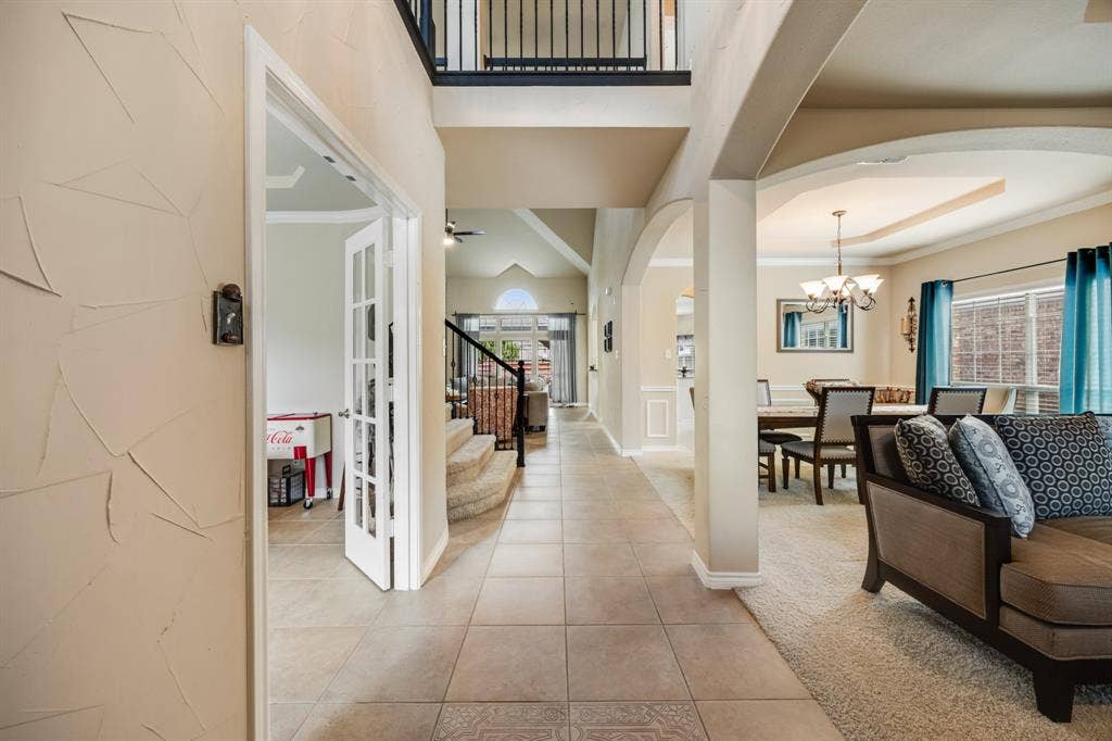 Entryway featuring arched walkways, tile patterned floors, stairway, a chandelier, and carpet flooring