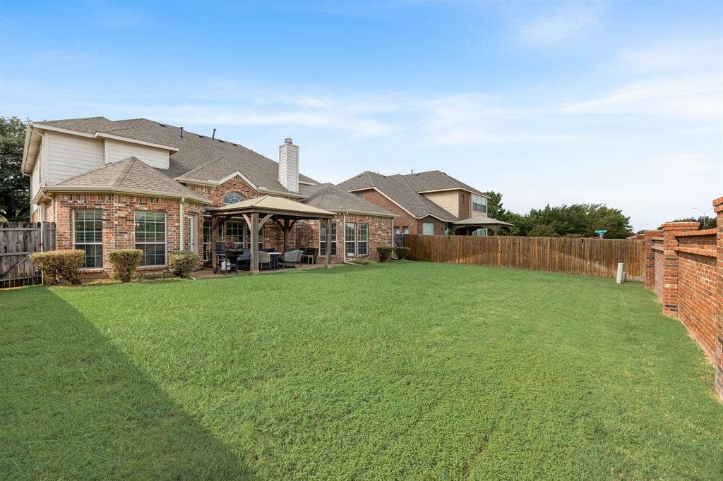 Fenced backyard featuring a patio area and a gazebo