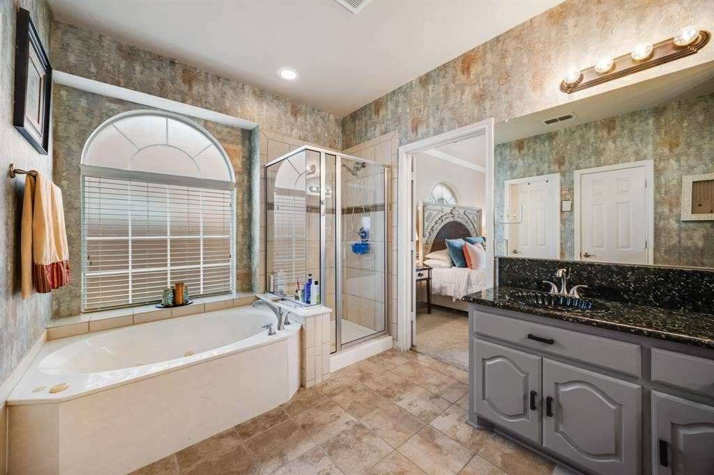 Bathroom featuring wallpapered walls, ensuite bathroom, a garden tub, vanity, and a shower stall