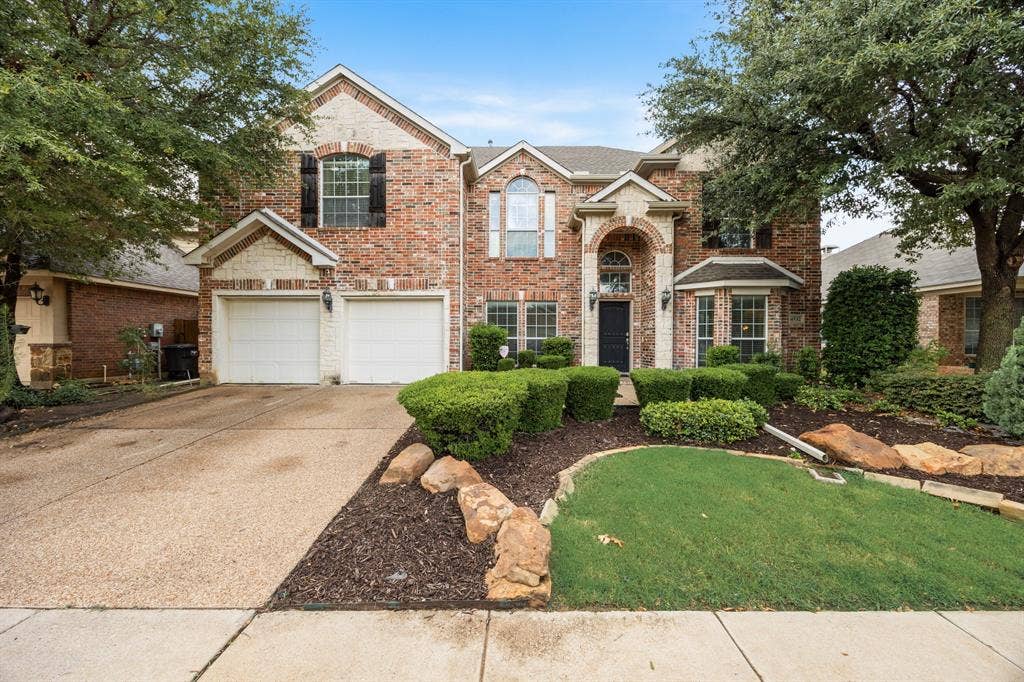 Traditional-style house featuring brick siding, driveway, an attached garage, a front yard, and a shingled roof
