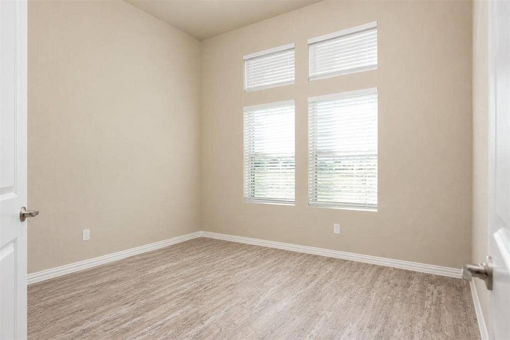 3704 Banton Street, Rowlett, TX 75089 Room featuring high ceilings, wood-finish flooring, and four stacked windows with horizontal blinds