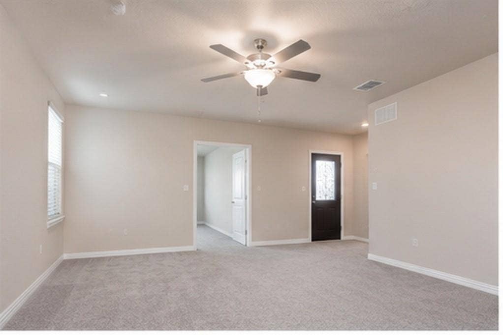 3704 Banton Street, Rowlett, TX 75089 Neutral-toned interior space featuring neutral wall paint, wall-to-wall carpeting, a ceiling fan with integrated lighting, and a dark-finished exterior door with a glass insert