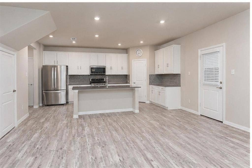 3704 Banton Street, Rowlett, TX 75089 Kitchen featuring white cabinetry, an island with stone-finish countertops, recessed lighting, and wood-finish flooring