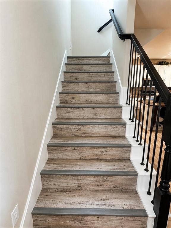 3704 Banton Street, Rowlett, TX 75089 Staircase featuring wood-finish treads, painted risers, and a matte black metal railing with a matching handrail