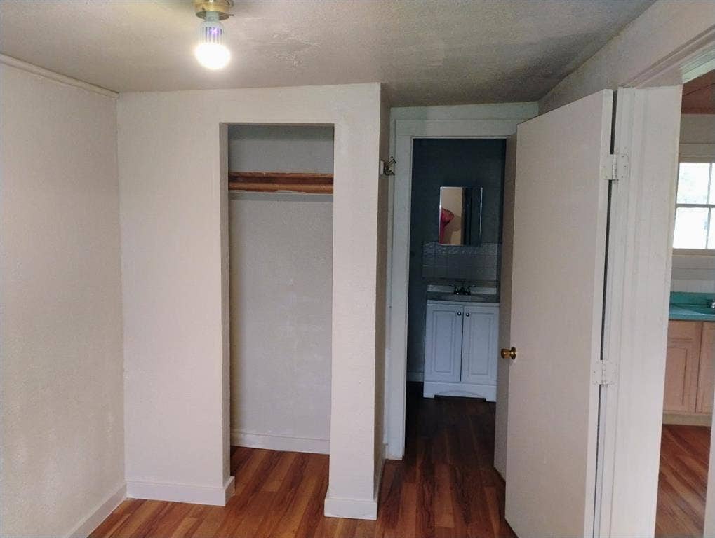 412 N Saint Augustine Drive, Dallas, TX 75217 Room featuring wood-finish flooring, a built-in closet with a wooden shelf, and a ceiling-mounted light fixture