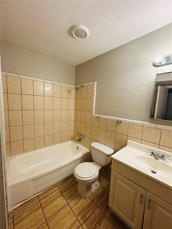 5317 Junius Street, #212, Dallas, TX 75214 Bathroom featuring a tub with tile surround, wood-finish tile flooring, a white vanity with an integrated sink, a wall-mounted mirror, and overhead lighting