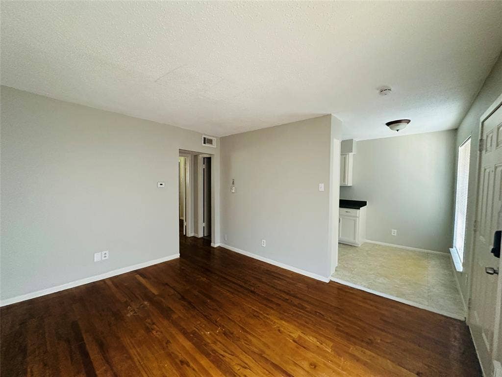 5317 Junius Street, #212, Dallas, TX 75214 Interior featuring wood-finish flooring, neutral wall paint, and white kitchen cabinetry with dark countertops