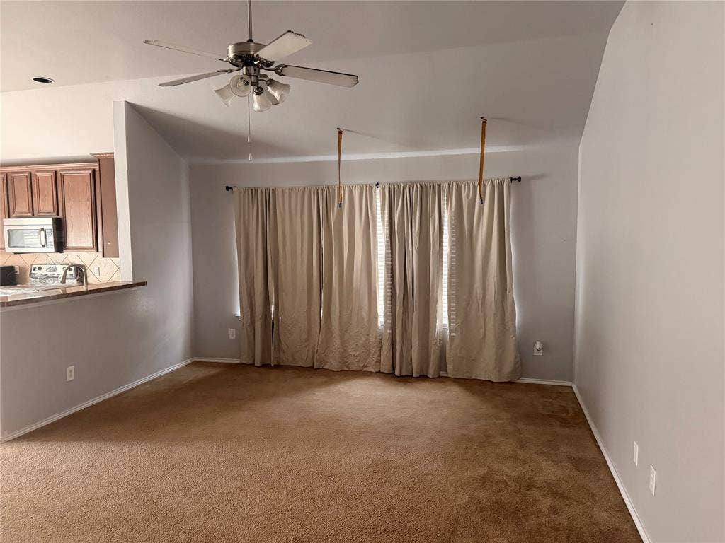 705 Bamboo Drive, Anna, TX 75409 Vaulted ceiling, carpeted flooring, brushed nickel ceiling fan with integrated lighting, and pass-through counter overlooking the kitchen area