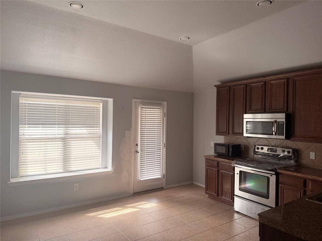 705 Bamboo Drive, Anna, TX 75409 Kitchen featuring vaulted ceilings, recessed lighting, tile flooring, dark-finish cabinetry, and stainless-steel appliances