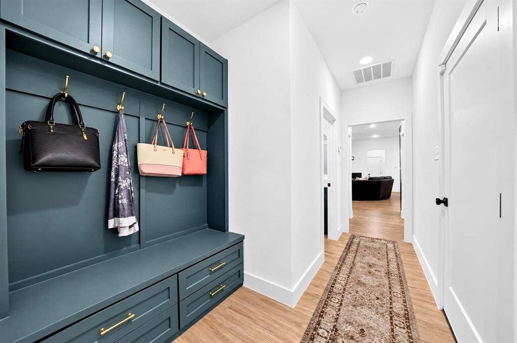 Built-in mudroom cabinetry featuring blue-painted millwork, brass-finish hardware, upper storage lockers, and lower drawer storage