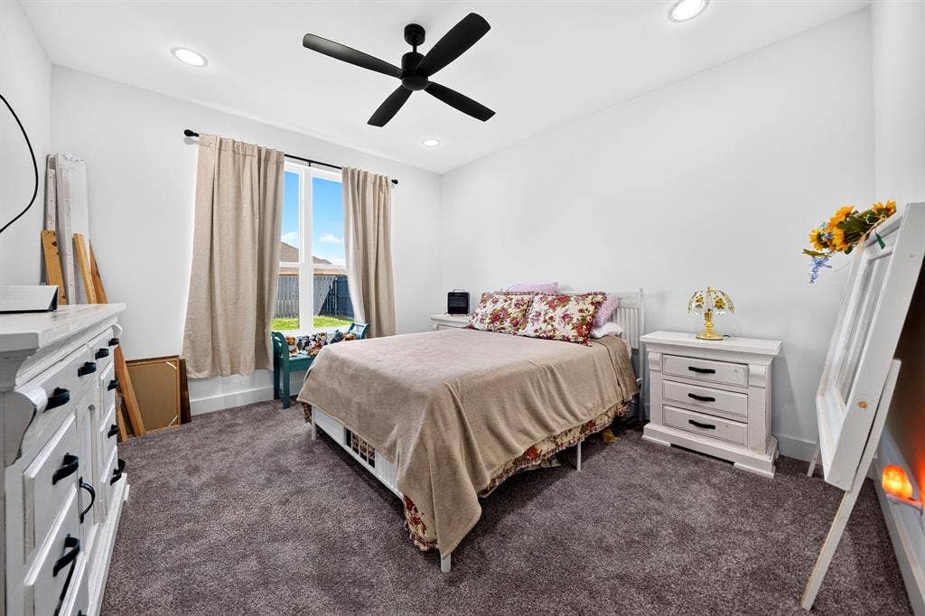 Neutral-toned interior featuring plush carpeting, recessed lighting, and a modern black ceiling fan