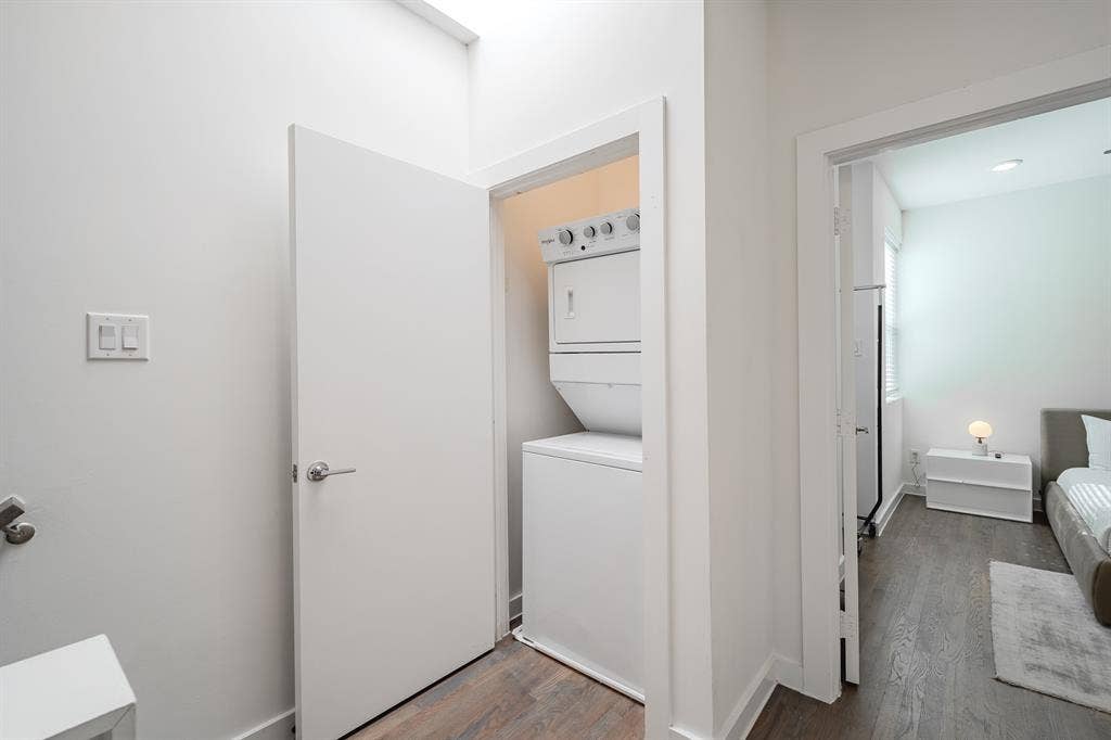 1502 Bennett Avenue, #106, Dallas, TX 75206 Laundry closet containing a stacked washer and dryer unit, featuring wood-finish flooring and a skylight