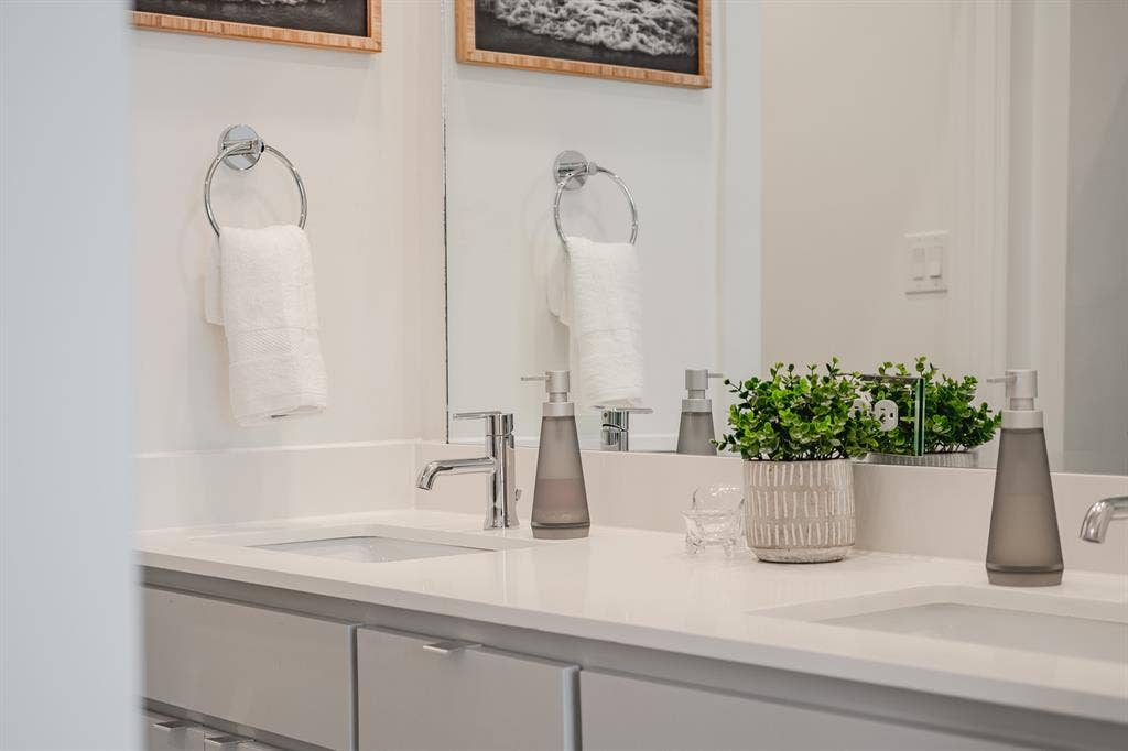 1502 Bennett Avenue, #106, Dallas, TX 75206 Double vanity featuring white solid-surface countertops, dual undermount sinks, chrome fixtures, and grey cabinetry