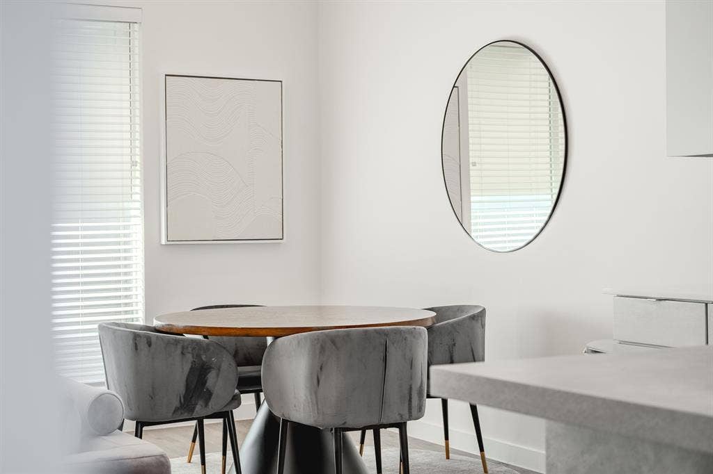 1502 Bennett Avenue, #106, Dallas, TX 75206 Neutral-toned interior space featuring horizontal slat blinds, a circular wall-mounted mirror with a black frame, and wood-finish flooring