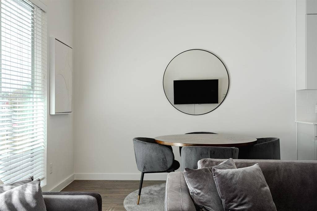1502 Bennett Avenue, #106, Dallas, TX 75206 High ceilings, large window with horizontal blinds, wood-finish flooring, and a circular wall-mounted mirror