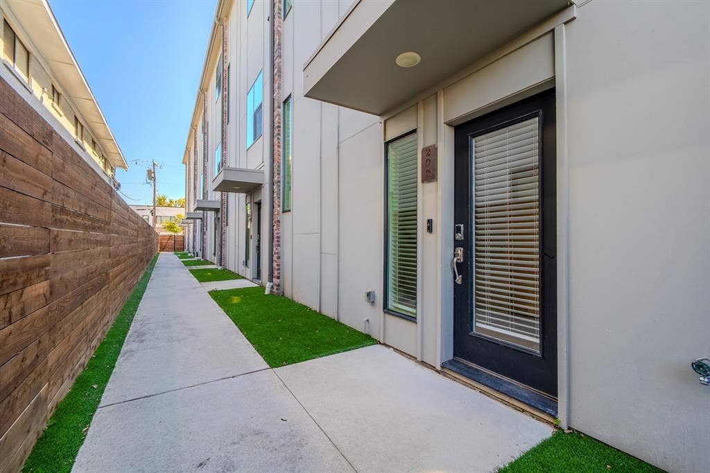 1502 Bennett Avenue, #106, Dallas, TX 75206 Modern exterior featuring smooth-finish paneling, vertical windows, a dark-finish entry door, and a horizontal wood-slat privacy fence