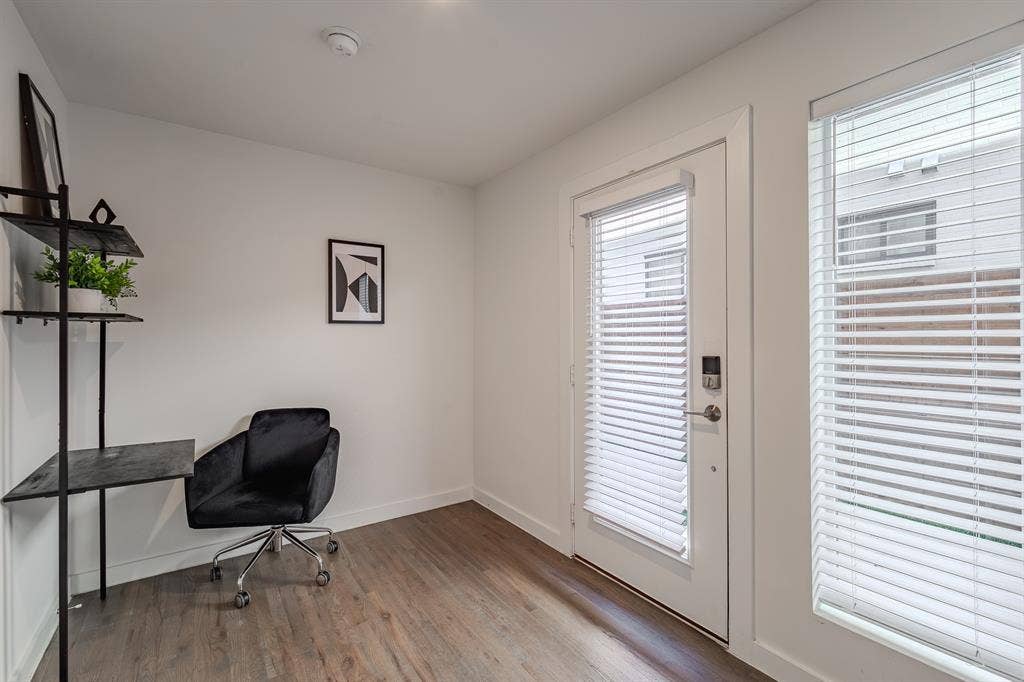 1502 Bennett Avenue, #106, Dallas, TX 75206 Interior space featuring wood-finish flooring, white walls, large window with horizontal blinds, and a glass-paneled exterior door with integrated blinds and electronic deadbolt hardware