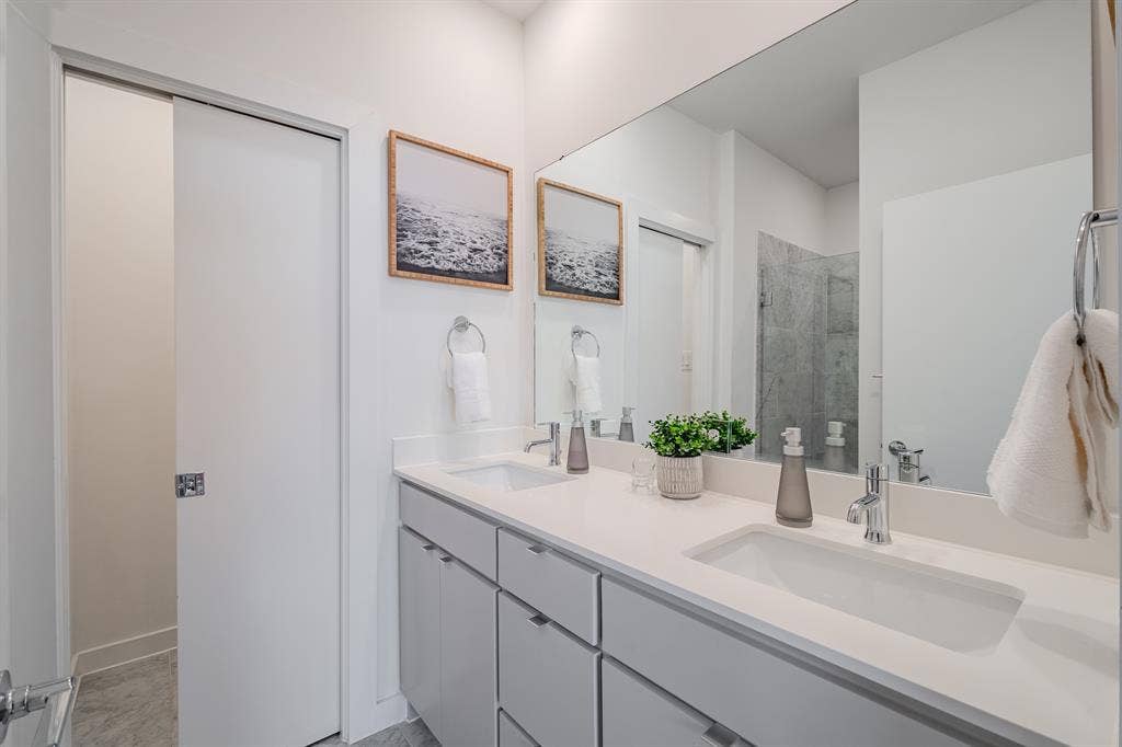 1502 Bennett Avenue, #106, Dallas, TX 75206 Dual-sink vanity featuring a solid surface countertop, undermount rectangular basins, chrome-finish fixtures, and a large-format vanity mirror
