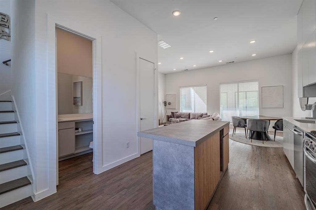 1502 Bennett Avenue, #106, Dallas, TX 75206 Kitchen island with concrete-finish countertop and wood-finish cabinetry, recessed ceiling lighting, wood-finish flooring, and high ceilings