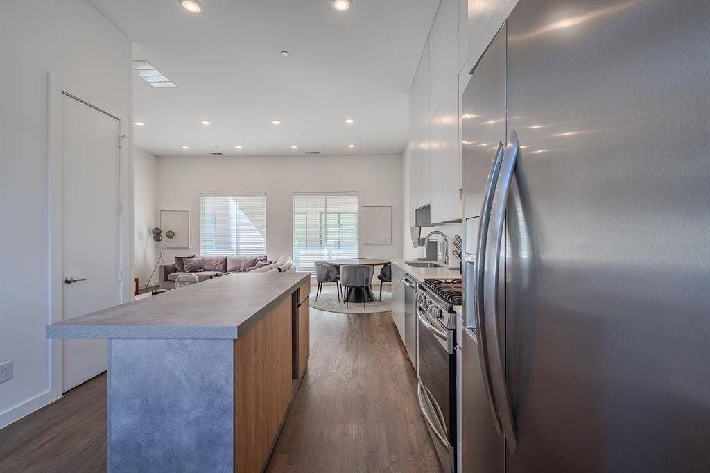 1502 Bennett Avenue, #106, Dallas, TX 75206 Kitchen island with concrete-style countertop and wood-finish cabinetry, stainless steel appliances, recessed ceiling lighting, and wood-finish flooring