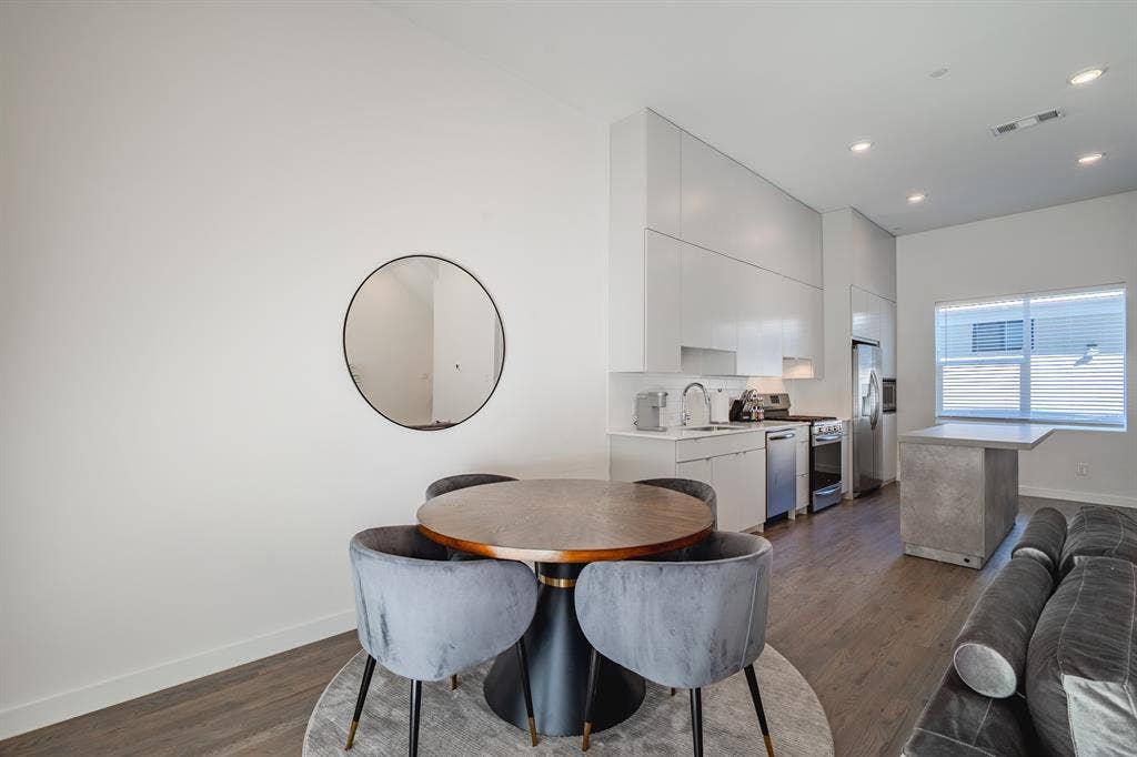 1502 Bennett Avenue, #106, Dallas, TX 75206 Kitchen featuring floor-to-ceiling cabinetry, stainless steel appliances, a stone-finish island, and wood-finish flooring with recessed lighting