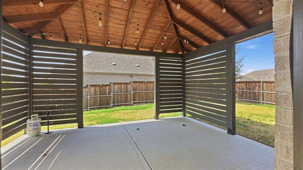 3129 Grayslick Avenue, Celina, TX 75009 Covered patio featuring a wood-plank ceiling, horizontal slat privacy screening, concrete flooring, and built-in string lighting