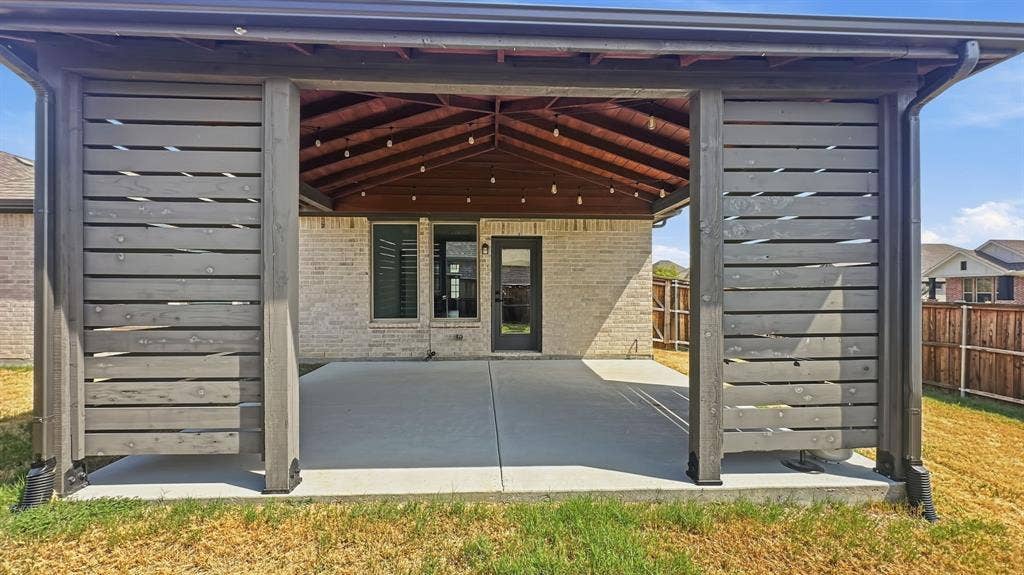 3129 Grayslick Avenue, Celina, TX 75009 Covered patio featuring a wood-planked vaulted ceiling, horizontal wood privacy screening, and a concrete slab foundation
