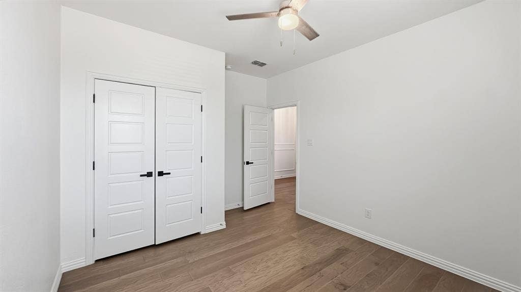 3129 Grayslick Avenue, Celina, TX 75009 Wood-finish flooring, double-panel closet doors with matte black hardware, and a ceiling fan with integrated lighting