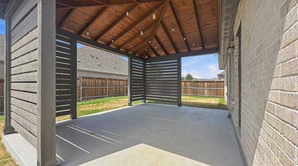 3129 Grayslick Avenue, Celina, TX 75009 Covered patio featuring a wood-plank ceiling, horizontal slat privacy screens, concrete flooring, and an exterior brick finish